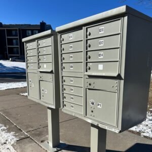 Apartment Complex with blue skies above in background of gray metal multiple commercial mailbox installation.