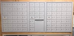 Wall of multiple gray metal mailboxes showing example of Commercial Mailboxes Installation.